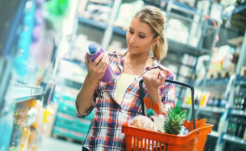 Mujer en el supermercado leyendo la etiqueta de un producto