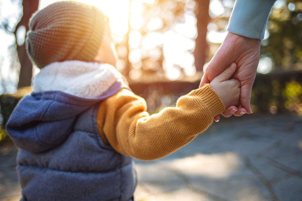 Niño de la mano de su madre por la calle