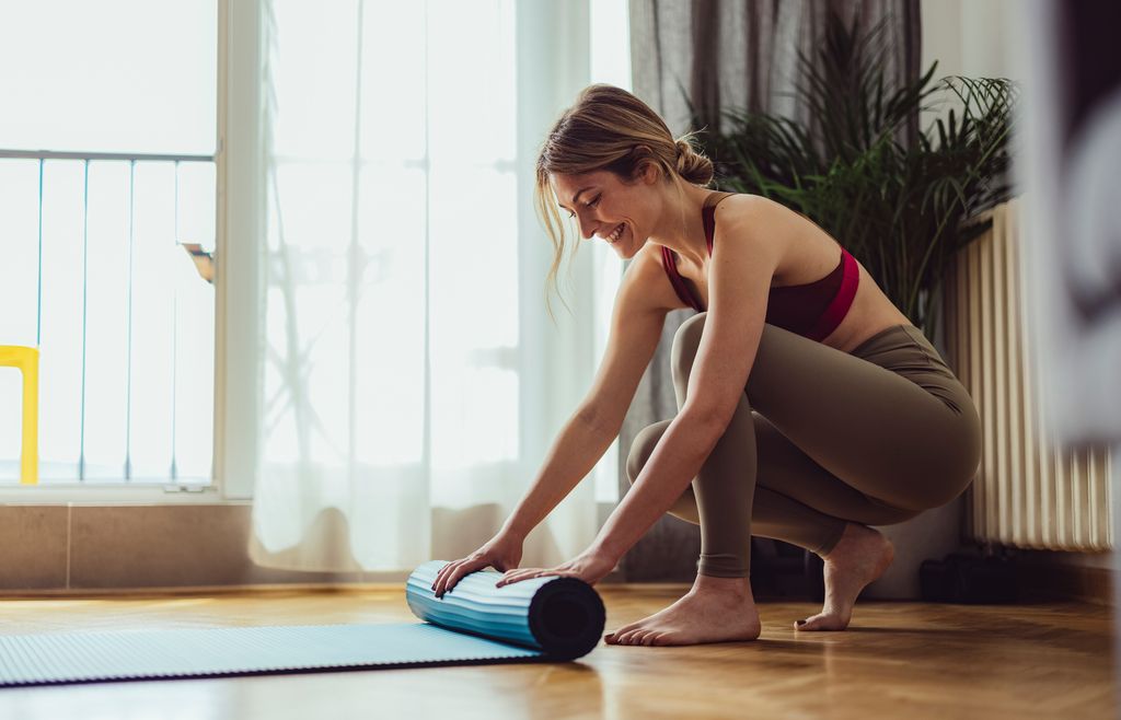 mujer extendiendo su esterilla para hacer ejercicio en casa