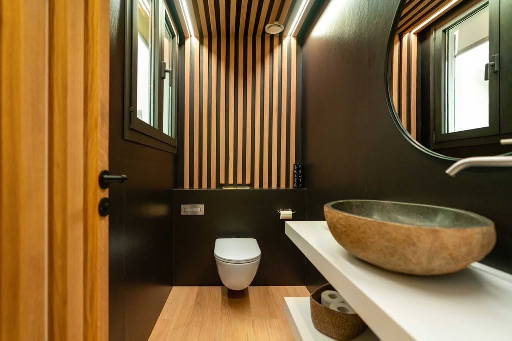 Baño con las paredes revestidas con listones de madera.