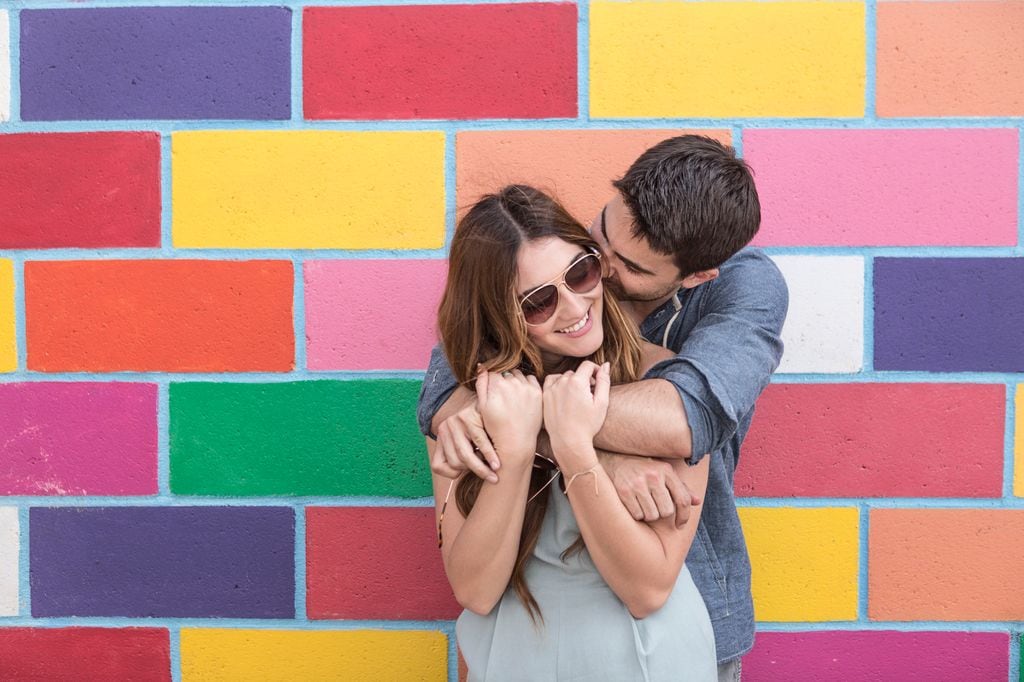 pareja feliz junto a una pared muy colorida