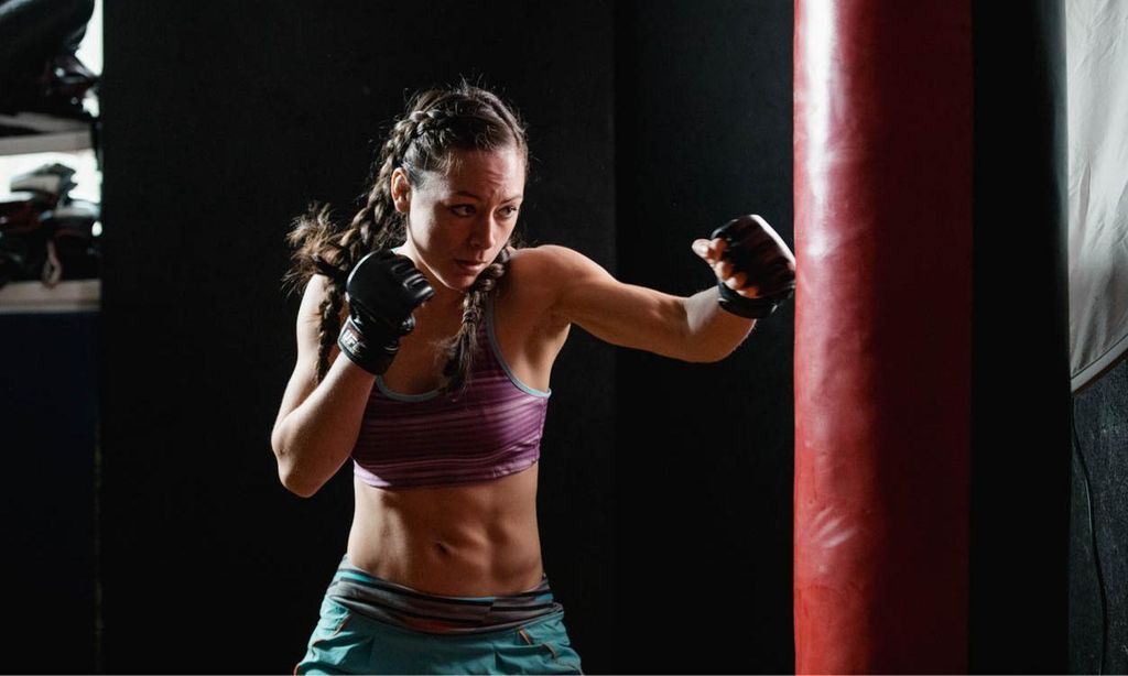 Mujer práctica boxeo frente a un saco.