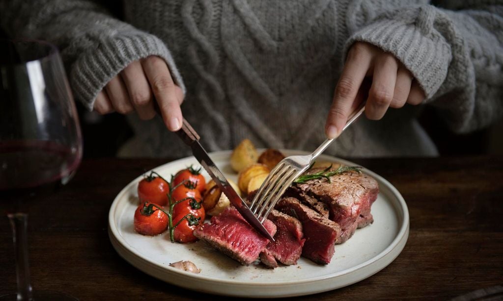 mujer cortando un troz de carne en un plato