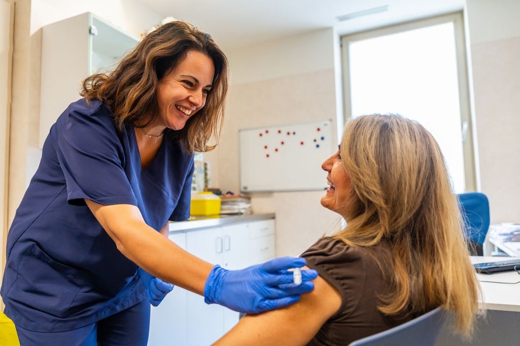 mujer en la consulta de la enfermera poniéndose la vacuna de la gripe