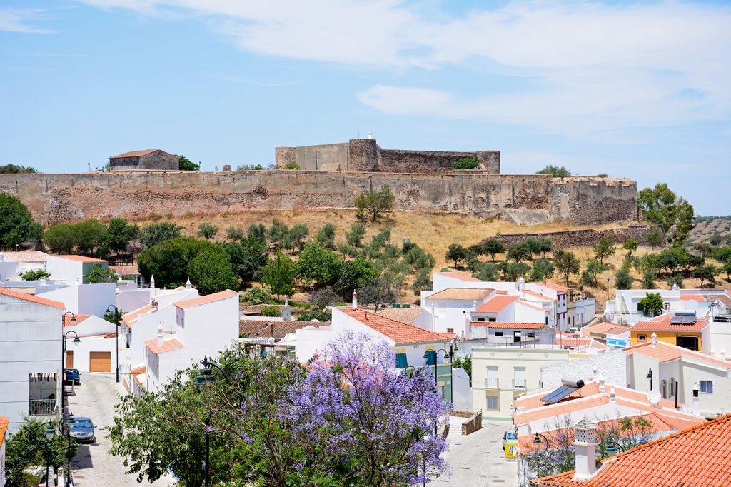 Vista elevada del castillo y los edificios de la ciudad con un bonito árbol Jacaranda en plena floración en primer plano, Castro Marim, Algarve, Portugal, Europa.