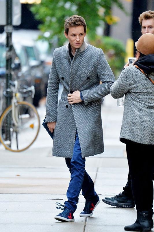 Eddie Redmayne con abrigo gris y sneakers Veja azules 