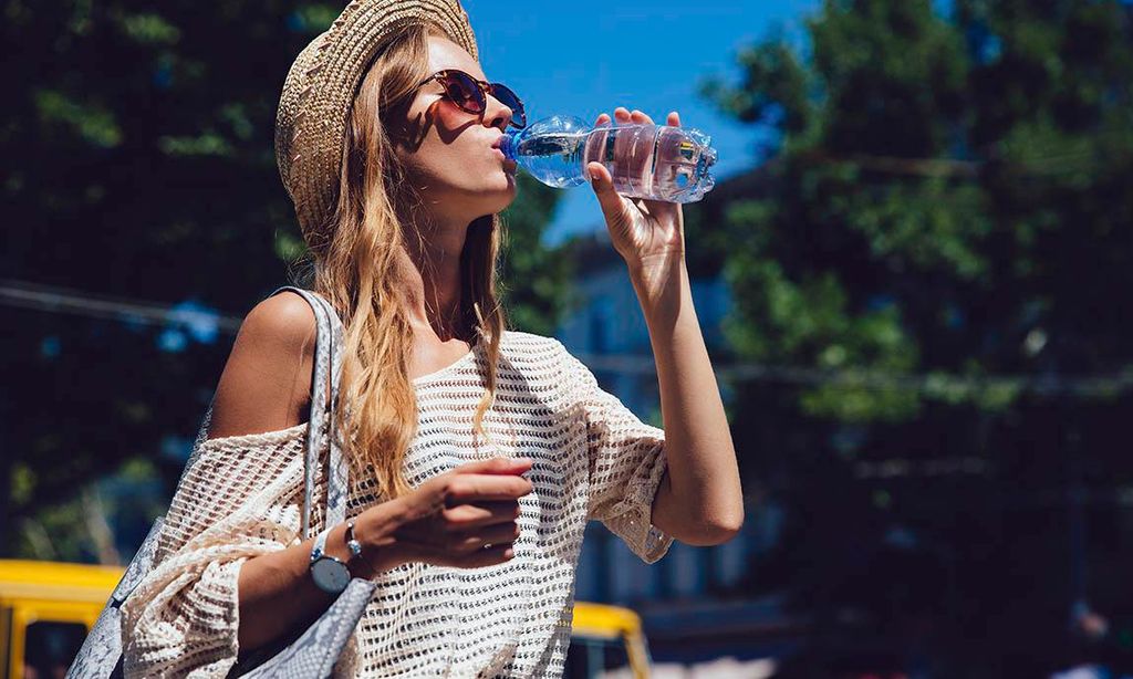 Mujer joven bebiendo agua de botella al aire libre