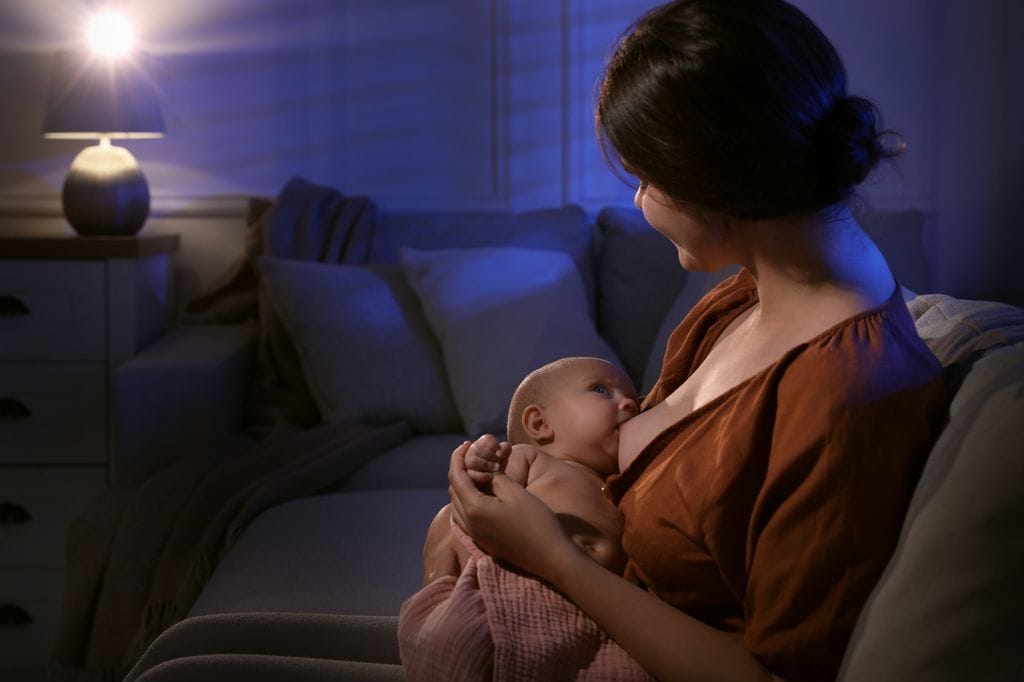 Mujer dando de mamar por la noche