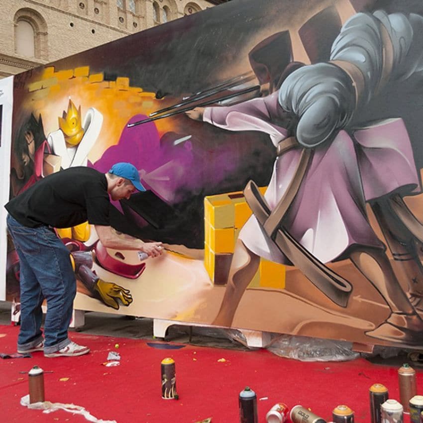 Artista urbano pintando un grafiti inspirado en una pintura de Goya.