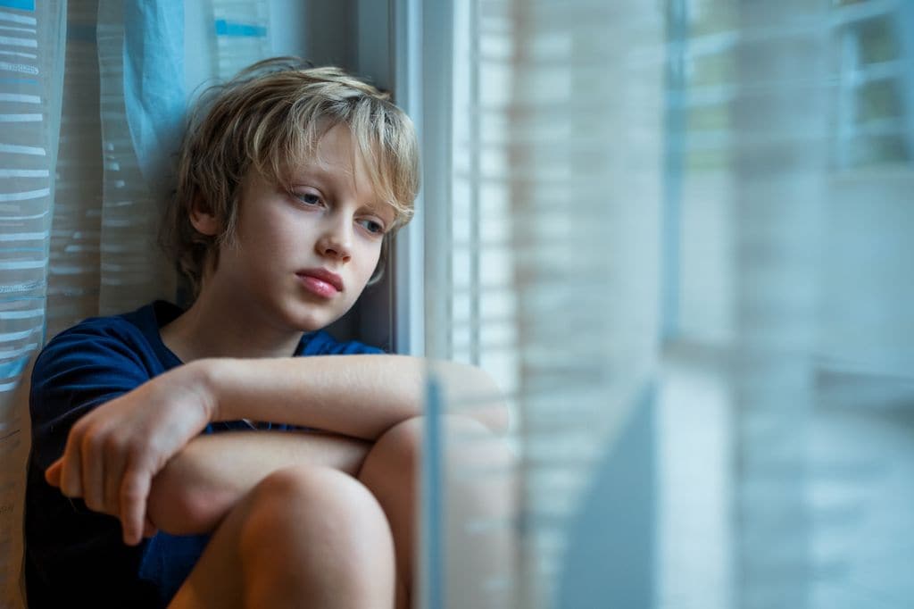 Niño deprimido junto a la ventana