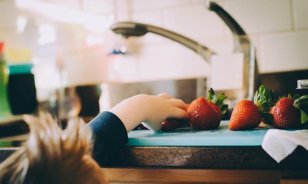 ni o cogiendo fresas en la encima de la cocina