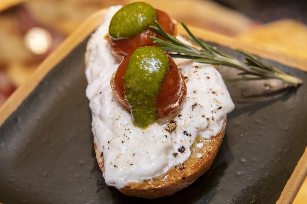 Tapa de queso Capri de leche cruda de cabra, con cremosa burrata, tomatitos semisecos y pesto genovés.