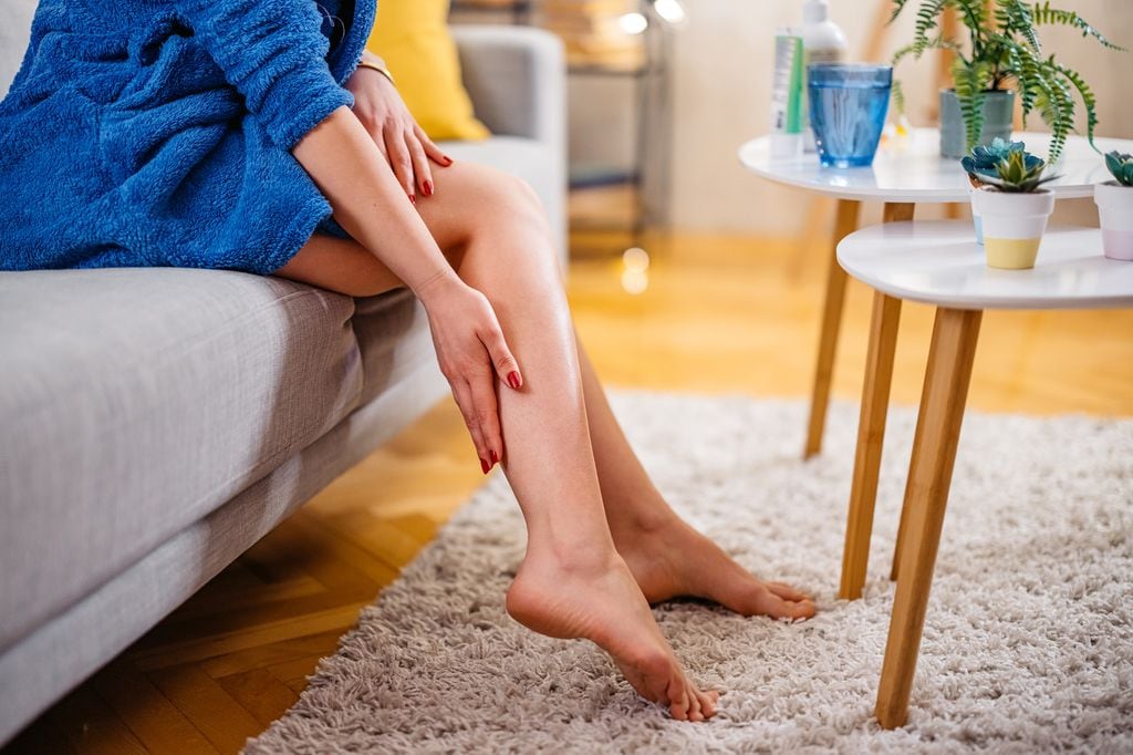 mujer tocándose las piernas antes de levantarse del sofá