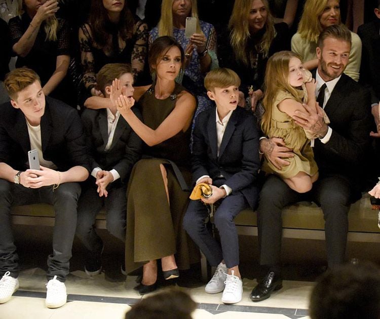 David y Victoria Beckham acompañados por sus cuatro hijos durante un desfile de moda
