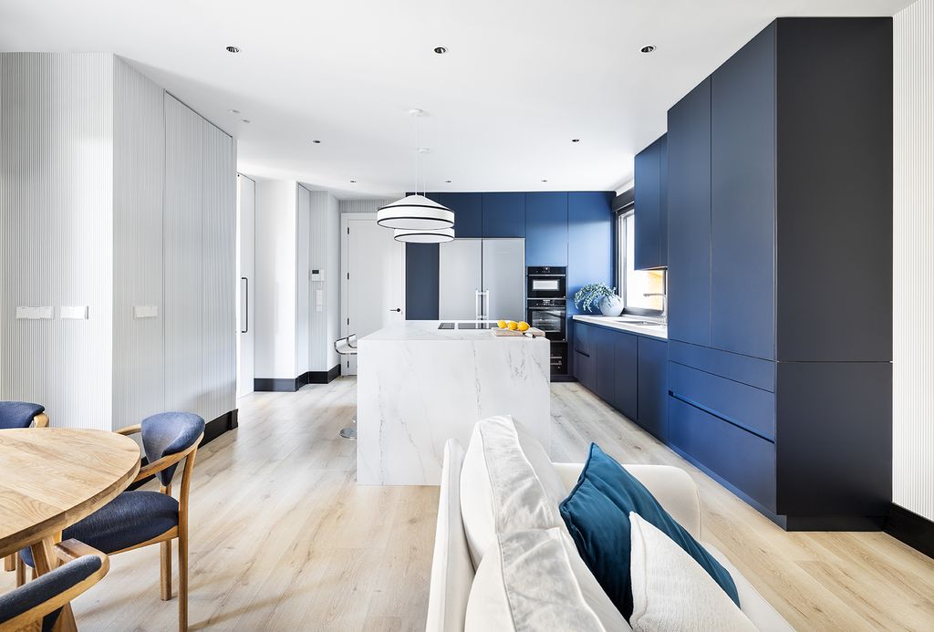 Cocina con muebles azules y blancos abierta al salón