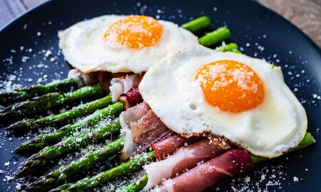 sunny side up eggs with asparagus and parmesan on wooden background