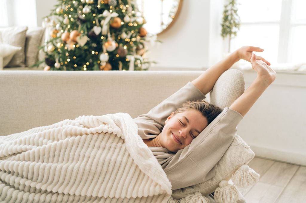 mujer relajada en casa, tumbada en el sofá, con el árbol de Navidad detrás