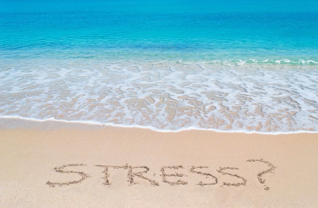 palabra estrés escrita en la arena de la playa, junto al mar