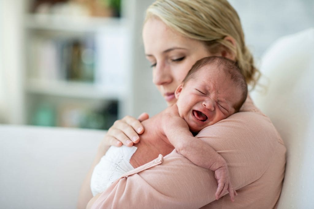 Recién nacido llorando en brazos de su madre