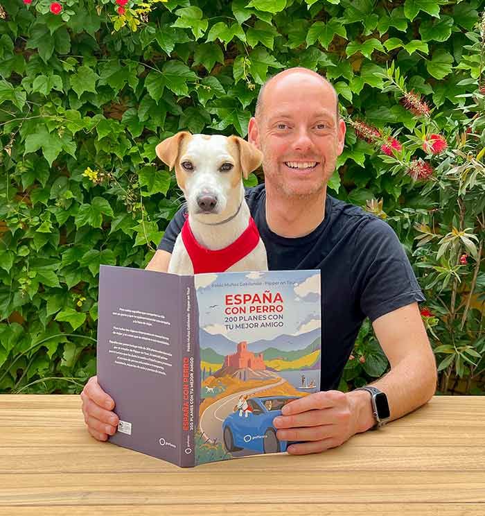 Pablo Muñoz posando junto a su amigo Pipper y el libro que juntos han elaborado para animar a las familias con perro a no dejar a sus mascotas en casa en vacaciones