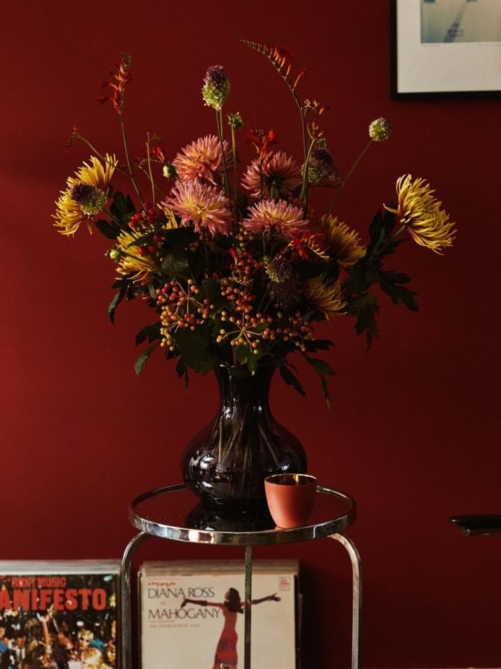 Jarrón con flores sobre pared granate