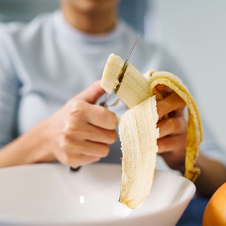 Mujer pelando y cortando un plátano