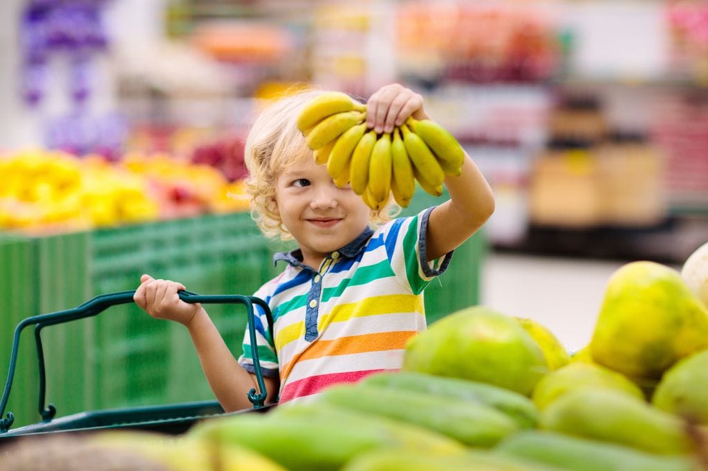 Niño comprando plátanos en el supermercado