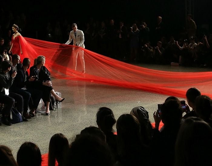 La modelo necesitó ayuda para desfilar con esta impresionante cola de tul en el mismo color rojo que el vestido; un color que es tradicional en las bodas celebradas en China, y que resuena con la acendencia de la diseñadora.
