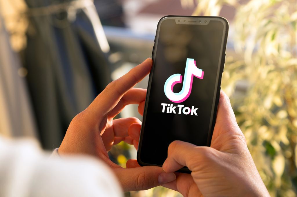 Mano de adolescente con un móvil con TikTok