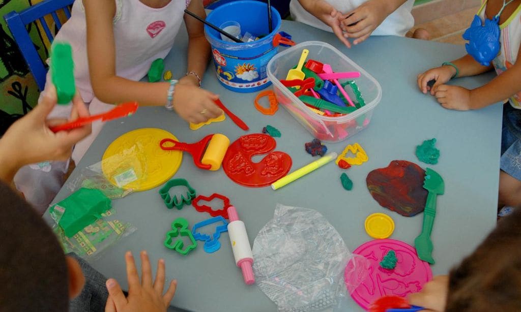 mesa con ni os y diferentes utensilios para jugar con plastilina