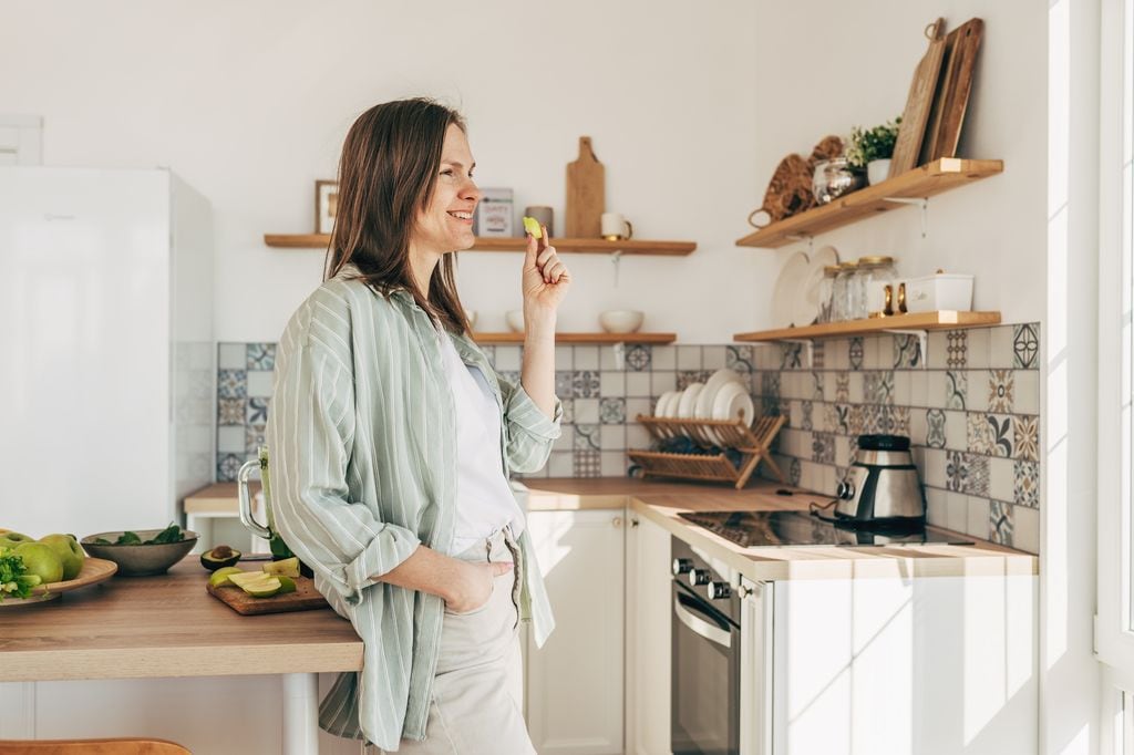 mujer feliz comiendo manzana en la cocina