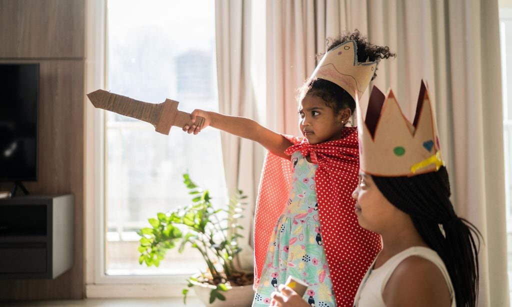 sisters playing with sword and wearing crown at home