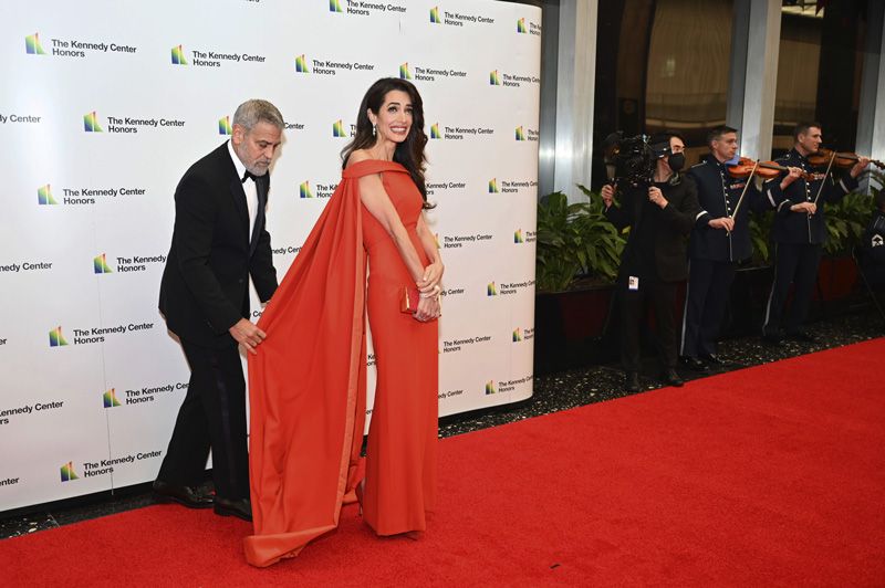 george clooney ayuda a Amal en la alfombra roja con vestido rojo y capa