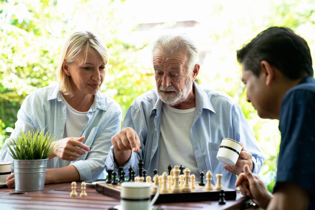 hombre anciano jugando al ajedrez con su familia