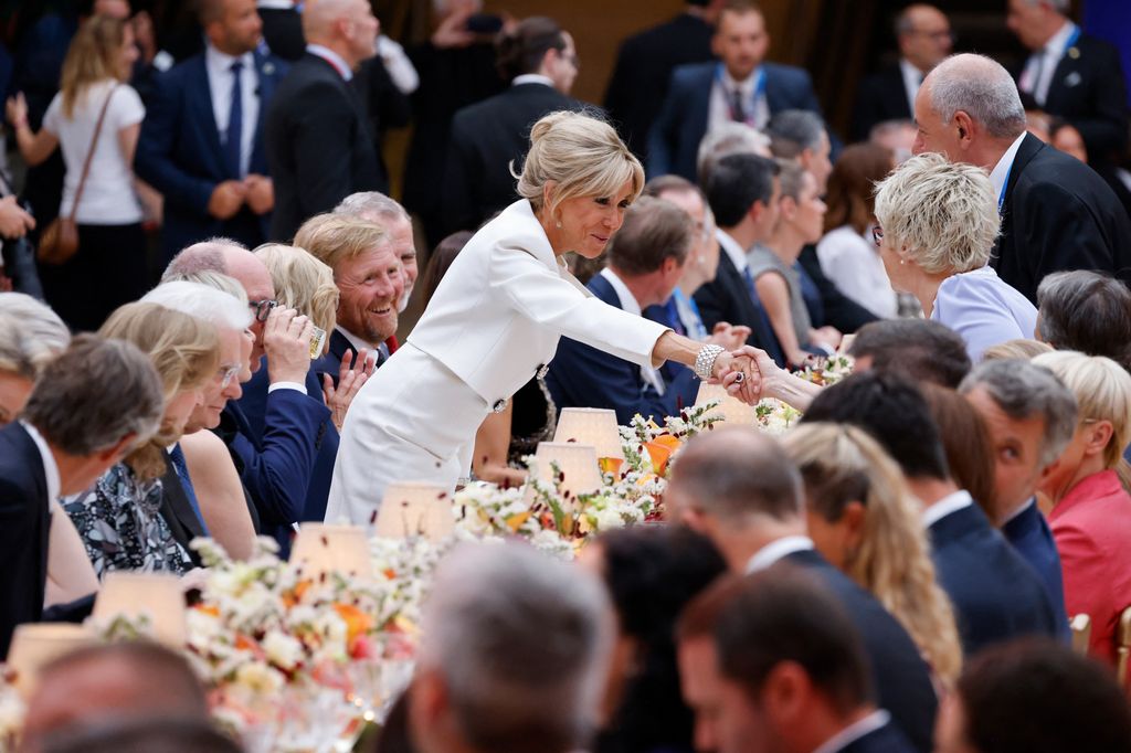 Brigitte Macron se levanta para estrechar la mano de uno de los invitados durante la cena
