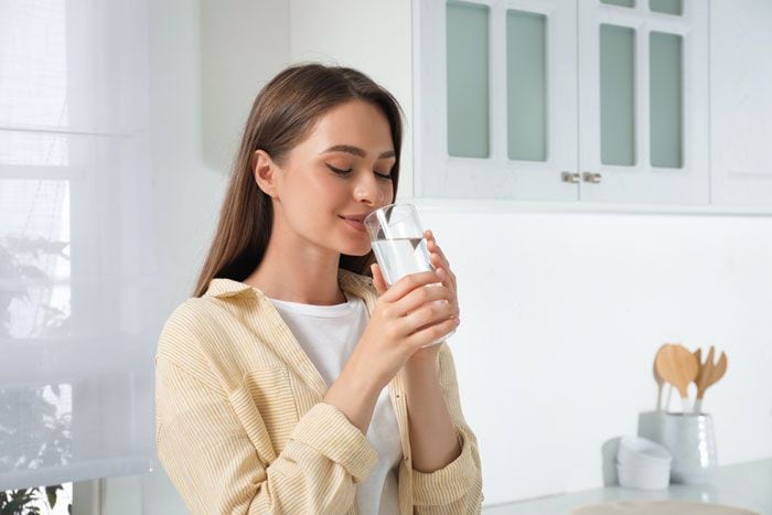 mujer bebiendo agua en la cocina