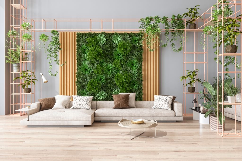 Sala de estar verde con jardín vertical, plantas de interior, sofá color beige y suelo de parquet