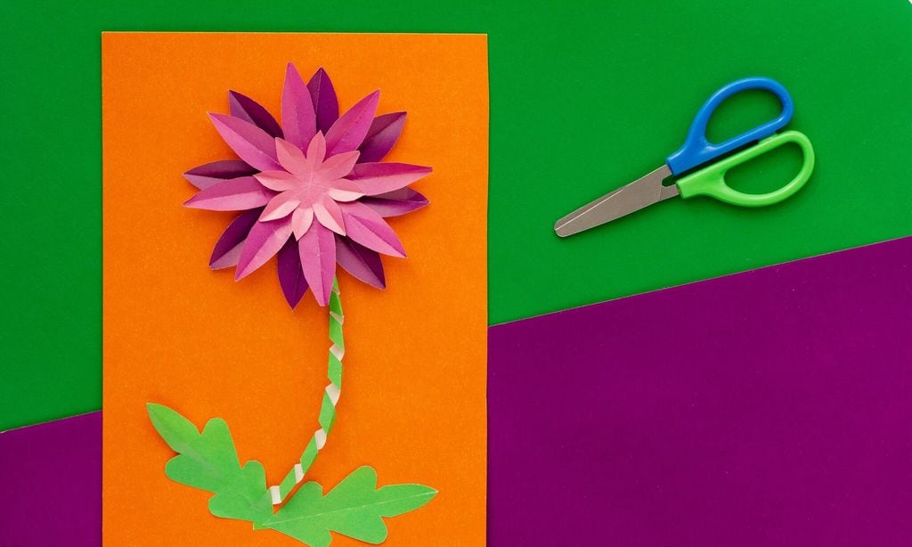 paper flower craft by child and scissors flat lay