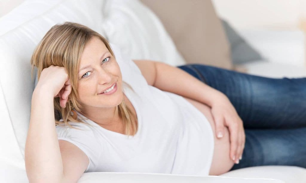 mujer embarazada tumbada feliz