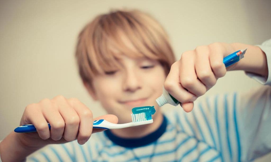 ni o poniendo pasta de dientes en cepillo