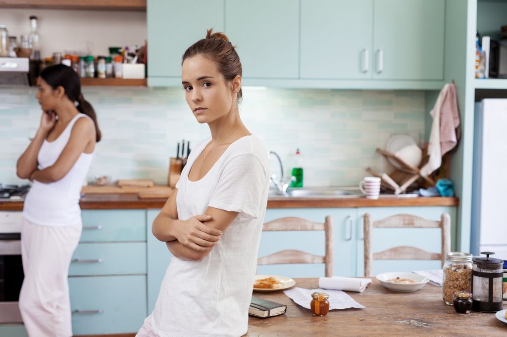 mujer preocupada en la cocina, con una amiga