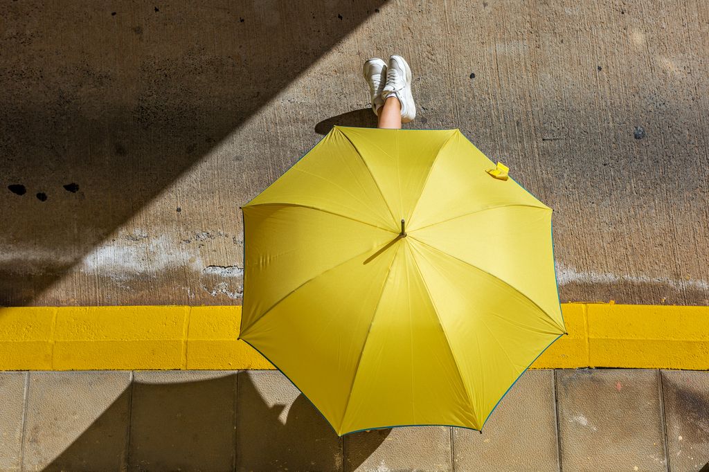 Pies asomando bajo un paraguas amarillo