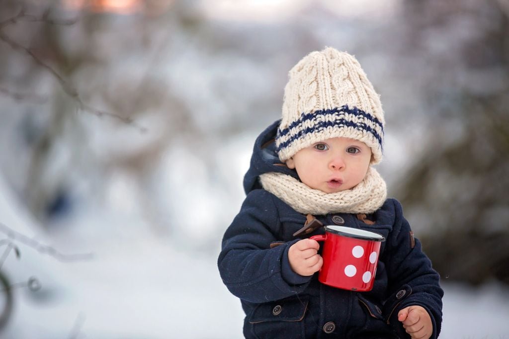 Niño pequeño en la nieve con gorro y bufanda