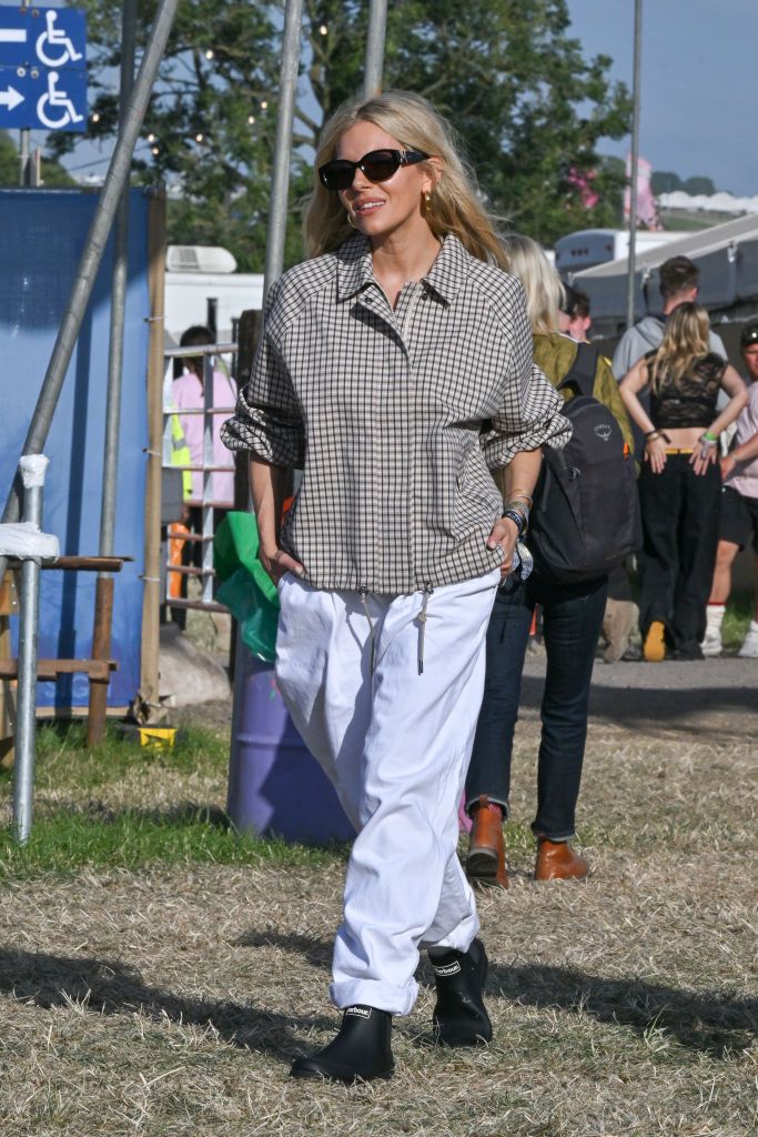 Sienna Miller en Glastonbury apuesta por 'baggy jeans', una cazadora impermeable con estampado de la marca británica 'Barbour' y botas de lluvia. 
