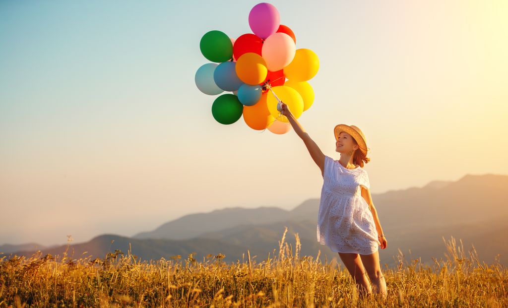 mujer feliz con globos de colores en el campo