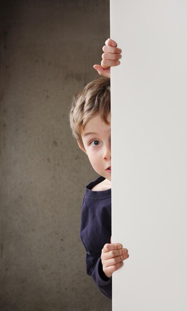 Niño escondido detrás de una puerta