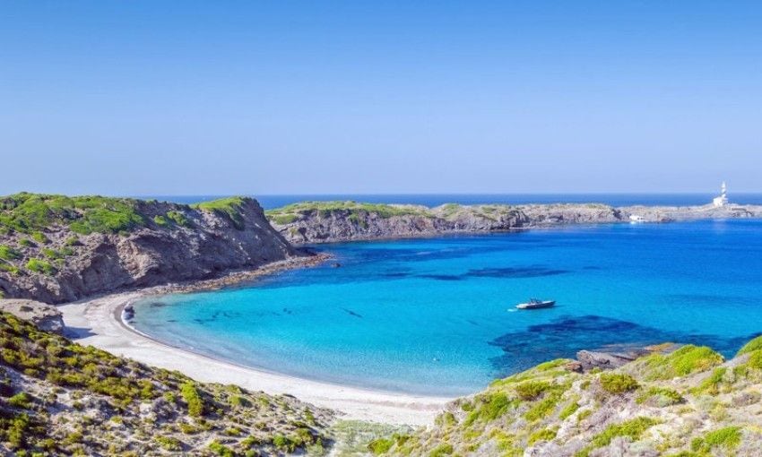 Cala Presili con vistas al Raco de Alga Morta y Faro de Favaritx en un día de verano.