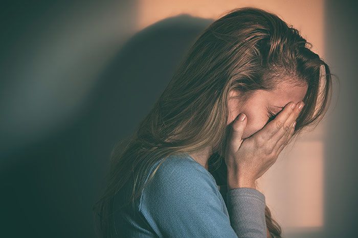 mujer tapándose la cara con las manos