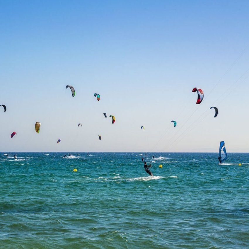 Deportistas practicando kitesurf en la playa de Valdevaqueros.
