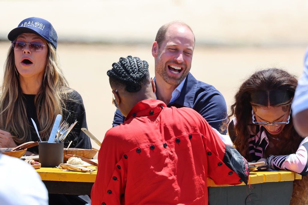 CAPE TOWN, SOUTH AFRICA - NOVEMBER 07: Prince William, Prince of Wales and Winnie Harlow join members of the local community for a traditional fish braai lunch during a visit to Kalk Bay Harbour to highlight the contributions of 2023 Earthshot Finalist, Abalobi on November 07, 2024 in Cape Town, South Africa. During his visit, The Prince of Wales attended the fourth annual Earthshot Prize Awards and engaged in various environmental initiatives and participated in events held in Cape Town as part of 'Earthshot Week'. (Photo by Chris Jackson/Getty Images)